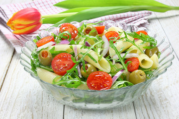 Salad with pasta, arugula, tomato, onion and green olives