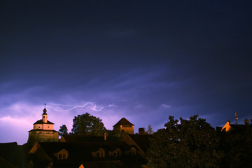 Storm lightning above old city with castle and a chapel