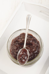 glass with plum jam and a small spoon