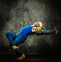 Obraz na płótnie Canvas Man dancer in cap and jacket showing break-dancing moves