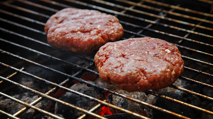 Raw beef burgers being broiled on the grill