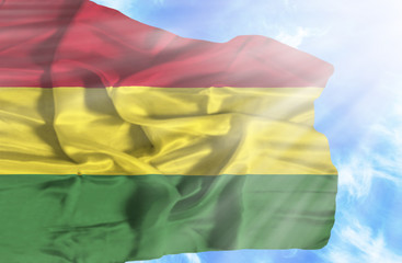 Bolivia waving flag against blue sky with sunrays