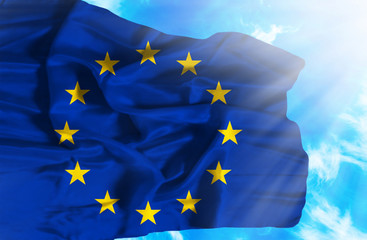 European Union waving flag against blue sky with sunrays