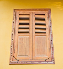 Wooden window on yellow cement wall