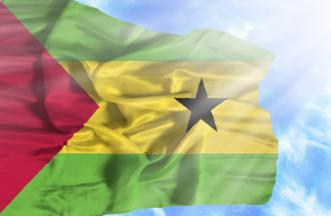 Sao Tome and Principe waving flag against blue sky with sunrays