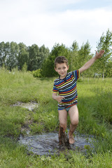 Barefoot boy runs through a puddle.