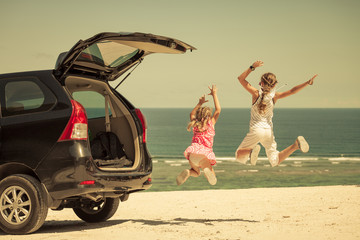 two sisters standing near a car on the beach
