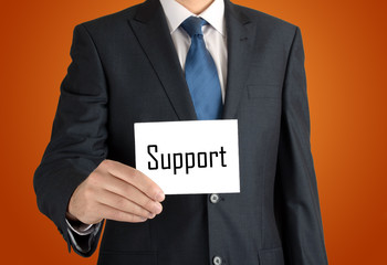 businessman holding a white sheet of paper with the inscription on orange background: support