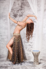 Retro belly dancer in backbend between drapes