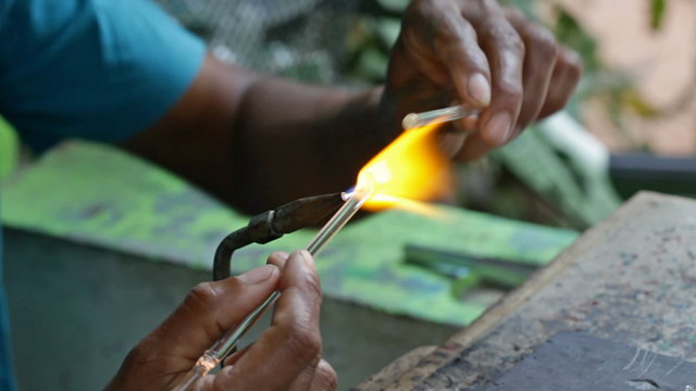 Glass blower rolling out an animal figurines made of glass
