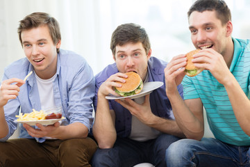 smiling friends with soda and hamburgers at home