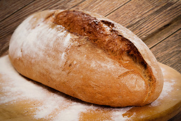 Homemade bread on wooden board, on table.