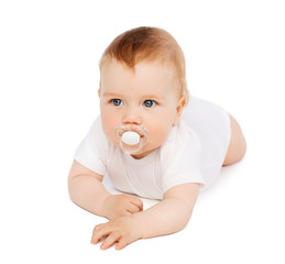 smiling baby lying on floor with dummy in mouth