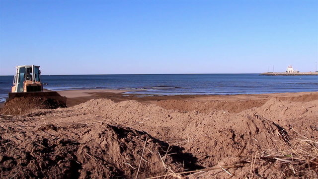 A bulldozer getting off soil by the beach