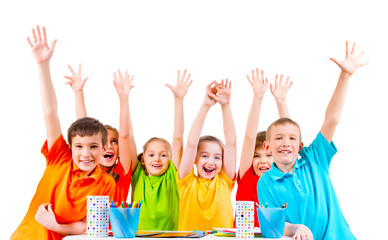 Group of children in colored t-shirts with raised hands.