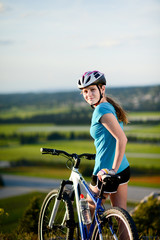 healthy cheerful young woman riding mountain bike countryside