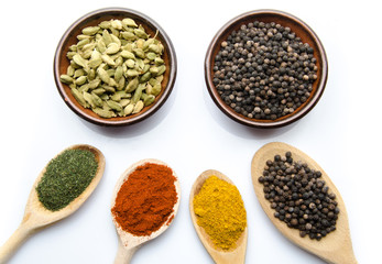 Composition of wooden spoons and cups with cardamom, pepper, dil