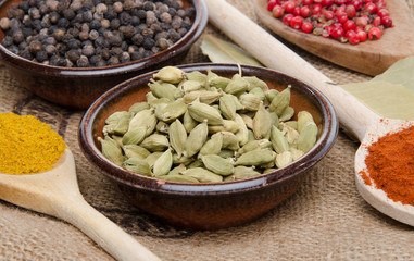 Composition of wooden spoons and cups with cardamom, pepper, pap