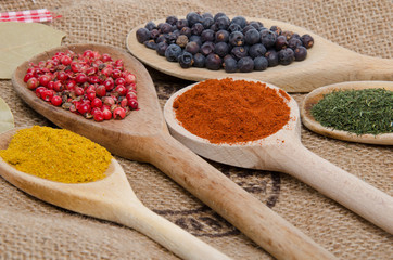 Composition of wooden spoons with juniper berries, paprika, pink