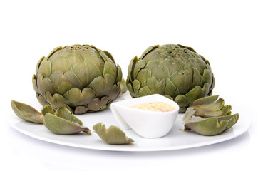 Obraz premium Cooked artichoke with a vinaigrette sauce on a plate