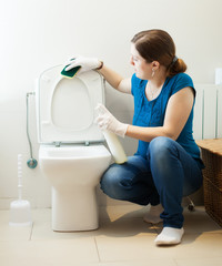 girl cleaning toilet seat with sponge and cleaner