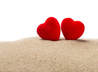Fototapeta premium two red hearts in the sand on a white