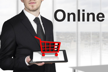 businessman holding tablet red cart standing in office online