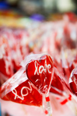 Red heart lollipop, with candies in background.