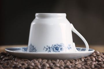 Coffee cup with coffee beans, on wooden table.