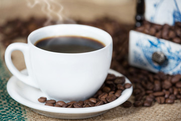 Cup of coffee,surrounded with coffee beans,on a wooden table.