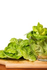 Lettuce in glass bowl, on wooden plate.