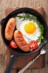 Fried egg sausages tomatoes in pan for breakfast