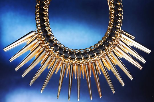 Shiny gold necklace on the blue background.