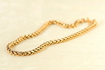 Fototapeta premium Golden necklace on the white textile.