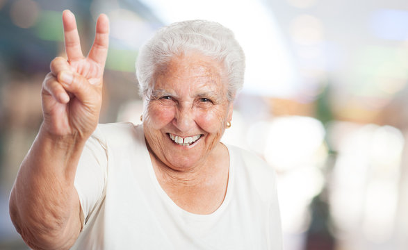 pretty old woman doing a victory gesture closeup
