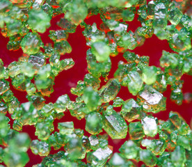 Green crystals on a red background. Extreme closeup. Macro