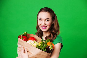 beautiful woman holding a bag full of vegetables