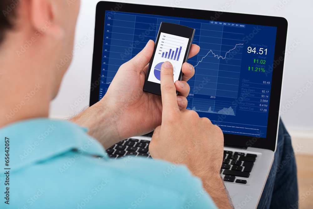 Poster man analyzing stock market using smartphone and laptop