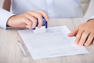 Cropped Image Of Businessman Stamping Contract Paper