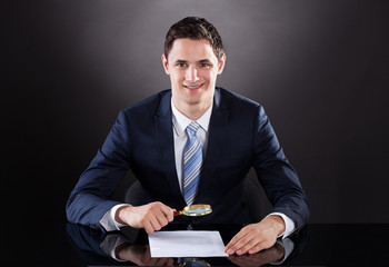 Businessman Examining Contract Paper With Magnifying Glass