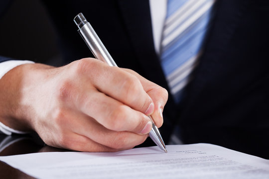 Businessman Signing Contract At Desk