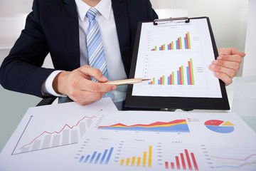 Confident Businessman Showing Graphs In Office