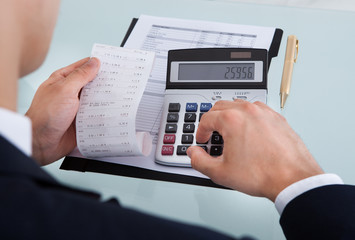 Businessman Holding Receipt While Calculating Expense In Office