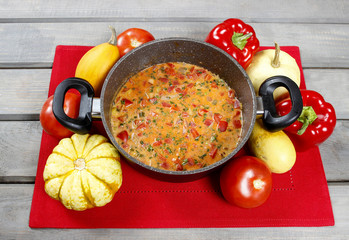 Pot of tomato soup on old wooden table