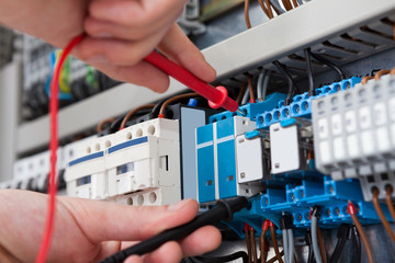 Electrician Examining Fusebox With Multimeter Probe