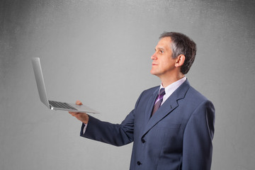 Handsome businessman holding modern laptop