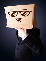 Businessman gesturing with a cardboard box on his head with smil
