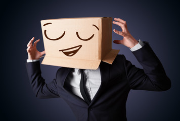Businessman gesturing with a cardboard box on his head with smil