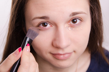 Makeup artist brush smears concealer on the eyelids model