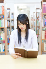 young asian woman reading a book in the library